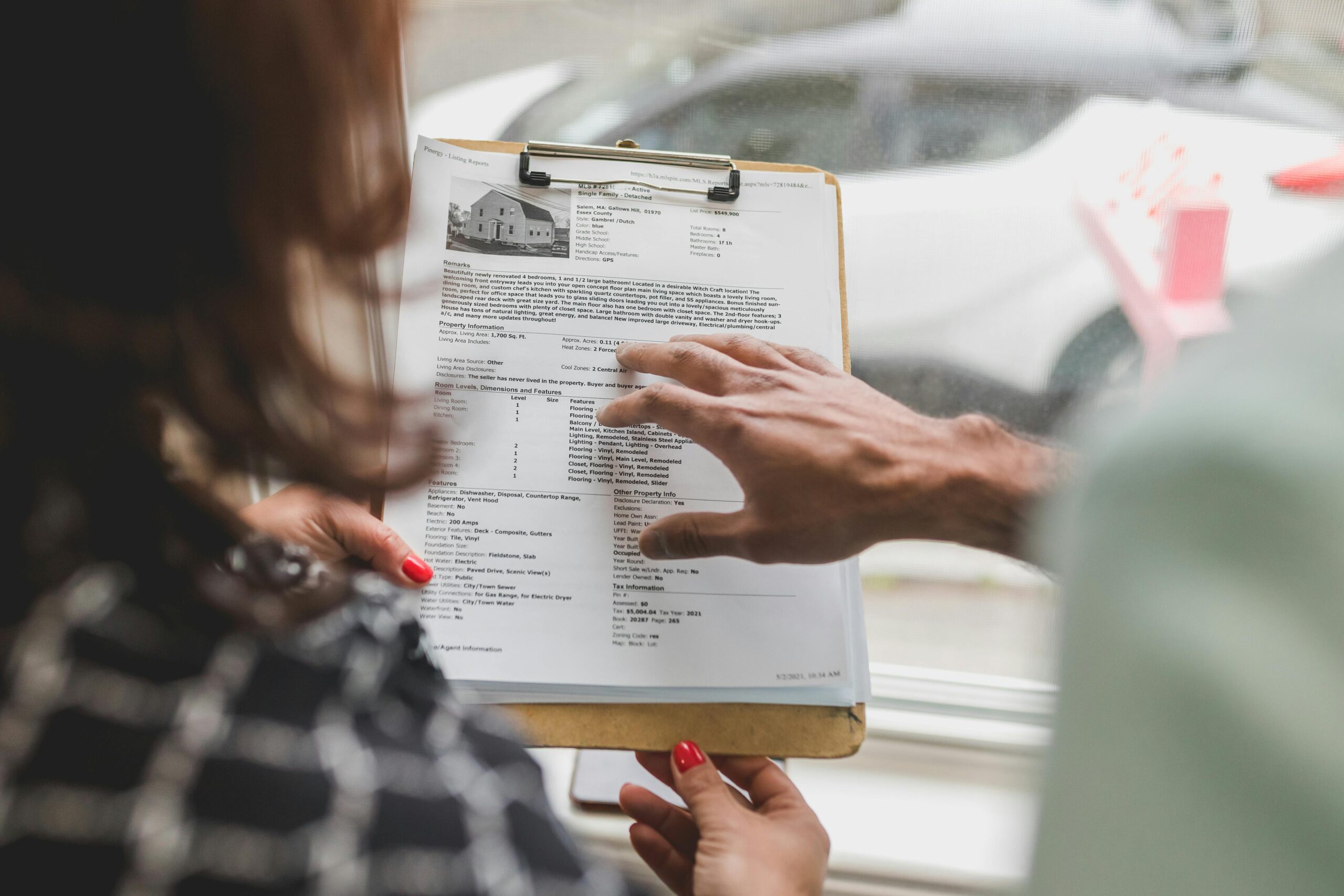 project-2 Real estate agent discussing property details with client using a clipboard indoors.